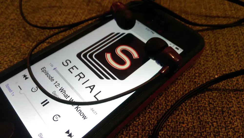 هاتف يعرض بودكاست Serial بجوار سماعات أذن